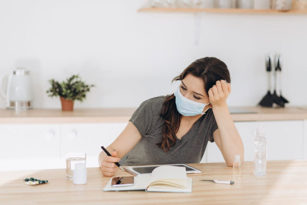 Coronavirus. Young business woman working from home wearing prot
